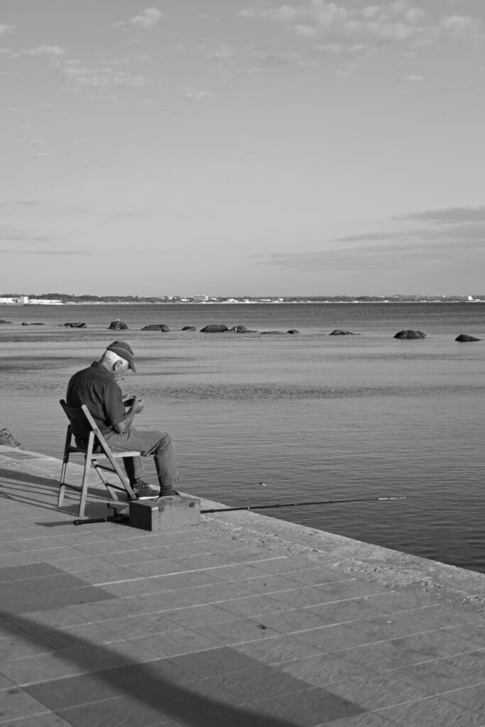 Older man sitting on pier fishing